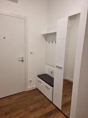 a room with white cabinets and a black bench at Skyline Lux Apartment by Planet Residence in Niš