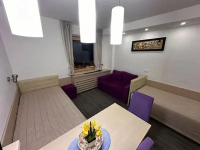 a living room with a table and purple chairs at Angela 103 in Kopaonik