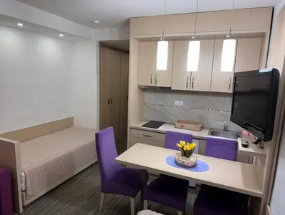 a room with a kitchen and a table with purple chairs at Angela 103 in Kopaonik