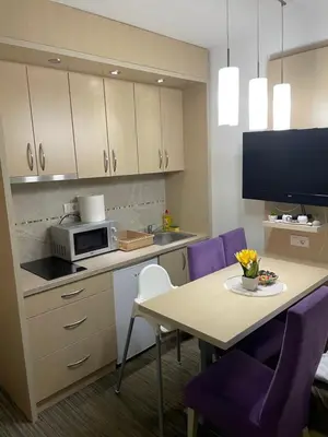 a kitchen with a table and a microwave and purple chairs at Angela 103 in Kopaonik