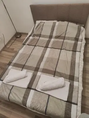 a bed with two folded towels on top of it at Konstantin Apartment in Niš