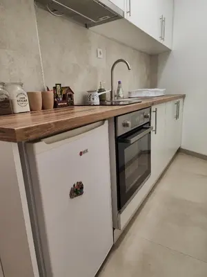 a kitchen with white cabinets and a wooden counter top at Konstantin Apartment in Niš
