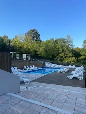 a swimming pool with white lounge chairs next to it at Apartman Eva in Vrnjačka Banja
