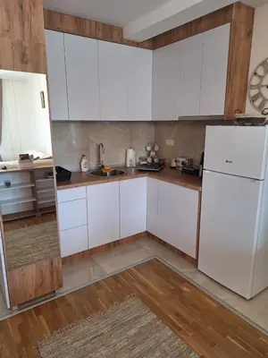 a kitchen with white cabinets and wooden floors at Apartman Eva in Vrnjačka Banja
