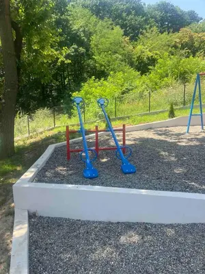 a park bench with two blue oars in the dirt at Apartman Eva in Vrnjačka Banja