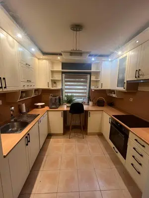 a kitchen with white cabinets and a chair in it at Prostran moderan apartman110 kvadrata u centru- 2 spavaće sobe, parking u dvoristu in Jagodina