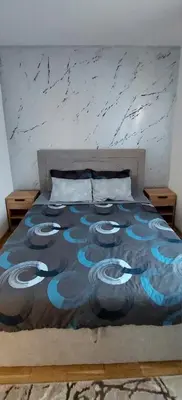 a bed with a blue and black blanket on it at Apartman K2 in Vrnjačka Banja