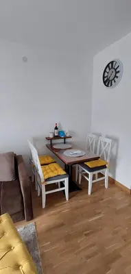 a living room with a table and chairs and a clock at Apartman K2 in Vrnjačka Banja