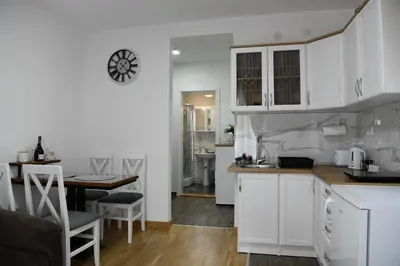 a kitchen with white cabinets and a dining table at Apartman K2 in Vrnjačka Banja