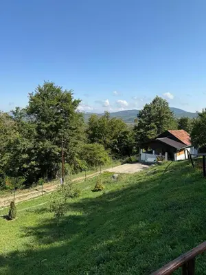a grassy field with a house in the background at Šumski mir in Despotovac