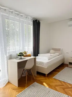 a white bedroom with a bed and a desk at Talia in Niš