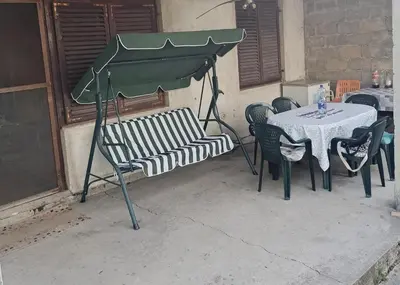 a table and chairs with a table and a green umbrella at Ivanka Apartmani in Bukorovac
