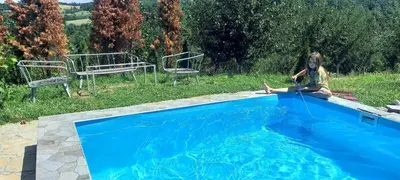 a girl sitting on the side of a swimming pool at Negovanovic Vikendica in Bukorovac