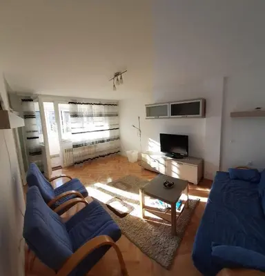 a living room with a blue couch and a tv at M&Z Apartments in Niš