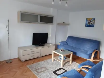 a living room with a blue couch and a tv at M&Z Apartments in Niš