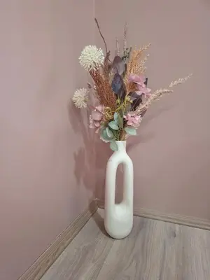 a white vase with a bunch of flowers in it at Apartman Dora in Jagodina