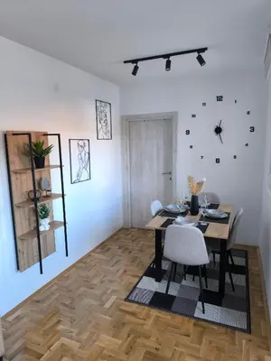 a dining room with a table and chairs and a clock on the wall at Apartman Stefani in Pirot
