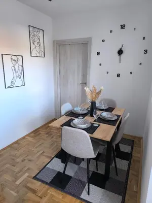 a dining room table with chairs and a clock on the wall at Apartman Stefani in Pirot