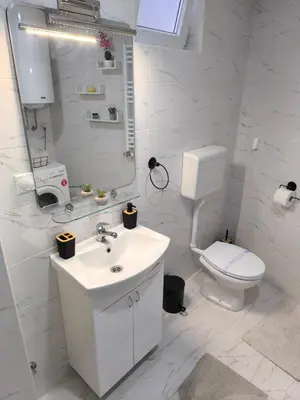 a white bathroom with a toilet and a sink at Apartman Stefani in Pirot