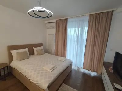 a bedroom with a bed and a large window at Komitet planet apartments, parking free in Niš