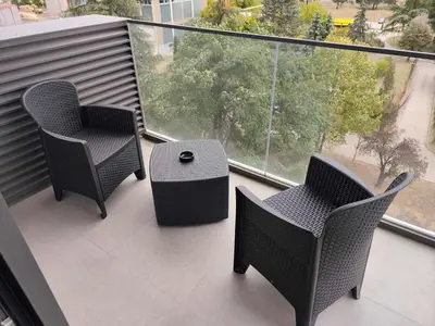a balcony with two chairs and a table and a window at Komitet planet apartments, parking free in Niš