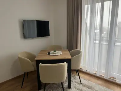 a dining room table with chairs and a television on a wall at Apartman Alibi in Kopaonik