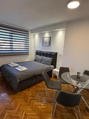 a bedroom with a bed and a table and chairs at Stošić Apartments in Zaječar