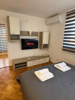 a bedroom with a tv and a bed with two towels at Stošić Apartments in Zaječar