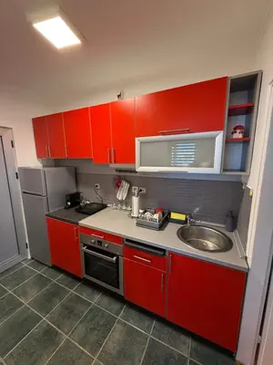 a kitchen with red cabinets and a sink at Stošić Apartments in Zaječar