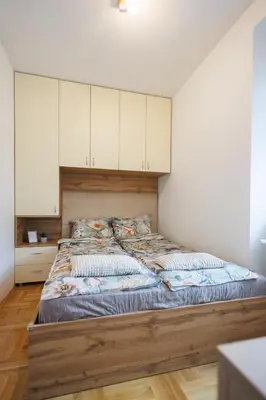 a bedroom with a large bed with white cabinets at M&M apartment in Pirot