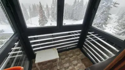 a room with two windows and a bench in front of snow at Apartman Bjanka 308 in Kopaonik