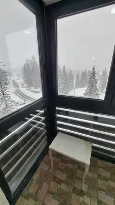 a bench sitting in a room with two windows at Apartman Bjanka 308 in Kopaonik