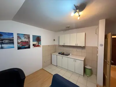 a kitchen with white cabinets and a ceiling at ROOF Apartman in Jagodina