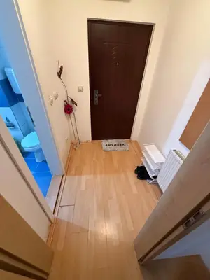 an empty hallway with a black door and a wooden floor at ROOF Apartman in Jagodina