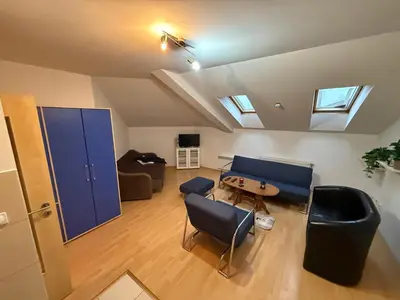 an attic living room with a table and chairs at ROOF Apartman in Jagodina