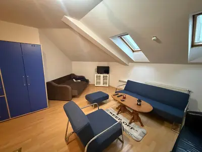 a living room with a blue couch and a table at ROOF Apartman in Jagodina