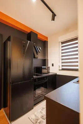 a kitchen with a stainless steel refrigerator and black cabinets at T & T Apartman - 2 bedrooms in Pirot