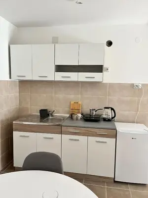 a kitchen with white cabinets and a sink at Apartman Ramonda in Niš