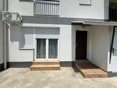 a white house with a door and a window at Apartman Ramonda in Niš