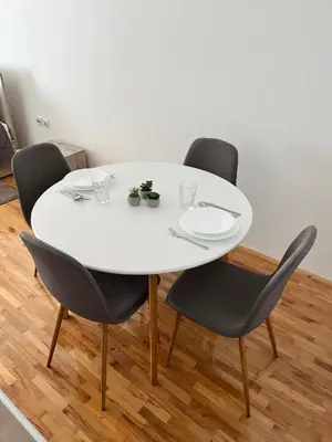 a table with four chairs and a white table with plates at Apartman Ramonda in Niš