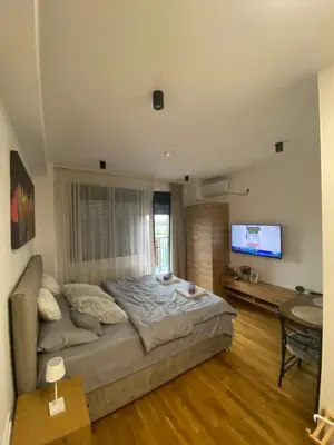 a bedroom with a bed and a table and a television at M&A apartman in Jagodina