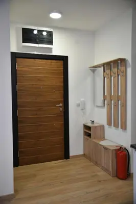 a bathroom with a wooden door and a red suitcase at Apartman Dimić, Vrnjačka Banja in Vrnjačka Banja