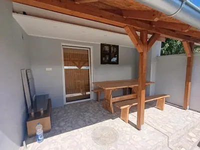 a patio with a wooden bench and a table at Apartman Marina i Sobe Luka in Bukorovac