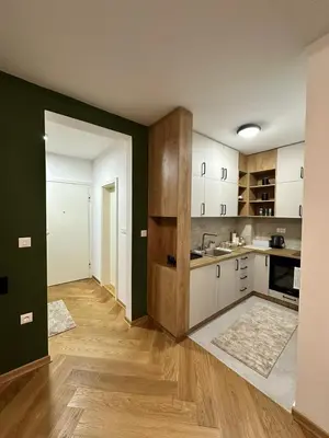 an empty kitchen with white cabinets and wood floors at Green Oasis in Vrnjačka Banja