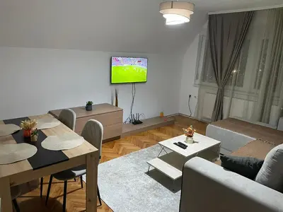a living room with a couch and a tv on the wall at Panorama centar, free parking in Niš
