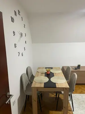 a dining room table with chairs and a clock on the wall at Panorama centar, free parking in Niš