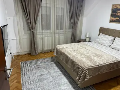 a bedroom with a large bed and a rug at Panorama centar, free parking in Niš