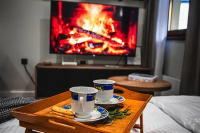 two cups and saucers on a coffee table in front of a tv at VujSki - Gondola Apartman in Brzeće
