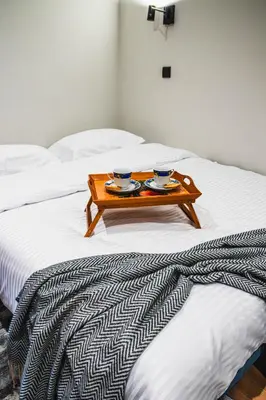 a wooden tray on a bed with two cups on it at VujSki - Gondola Apartman in Brzeće