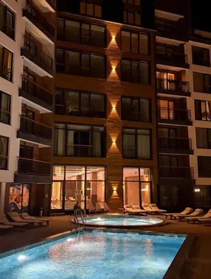 a building with a swimming pool in front of a building at Alpina Lux in Kopaonik